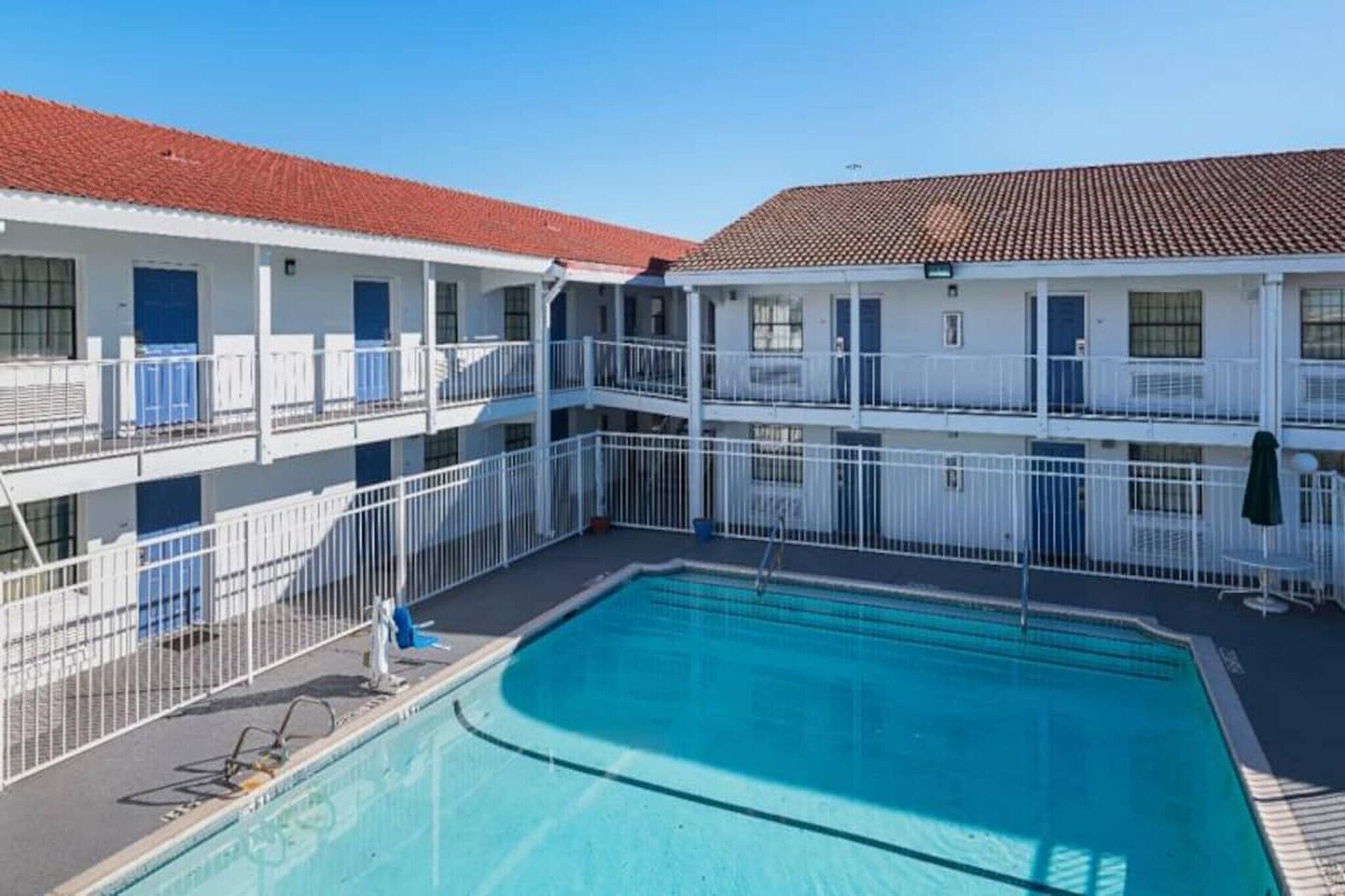 A hotel with a swimming pool, multiple balconies, and a red-tiled roof.