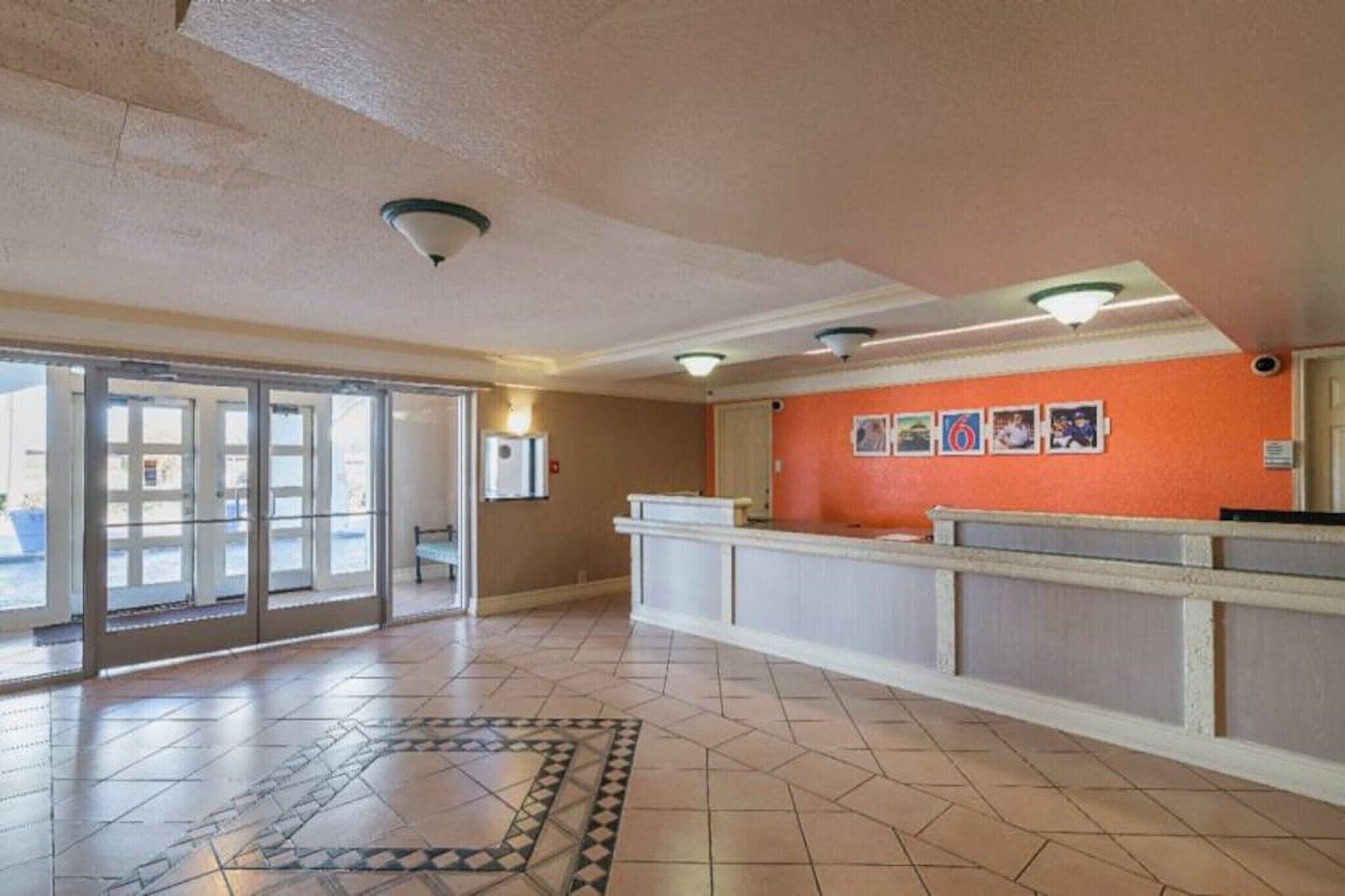 A reception area with a check-in counter, a patterned floor, and a door leading outside.