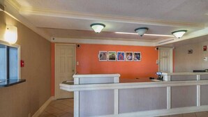 A reception area with a counter, a door, and a wall with framed pictures. - 2 FULL BEDS | NON-SMOKING (Grand Prairie)