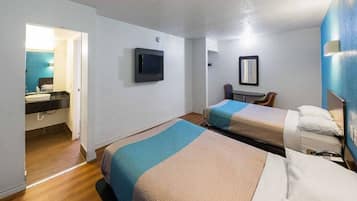 A hotel room with two beds, a TV, a small table, and a mirror.