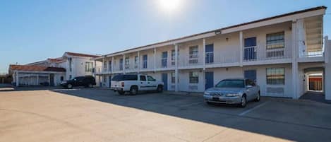 A motel with multiple rooms, a parking lot, and a clear sky.