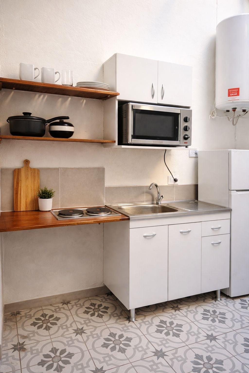 A compact kitchen with white cabinets, a microwave, a sink, and a stove.