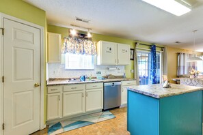 Una cocina con armarios blancos, lavavajillas y una pared de acento azul.