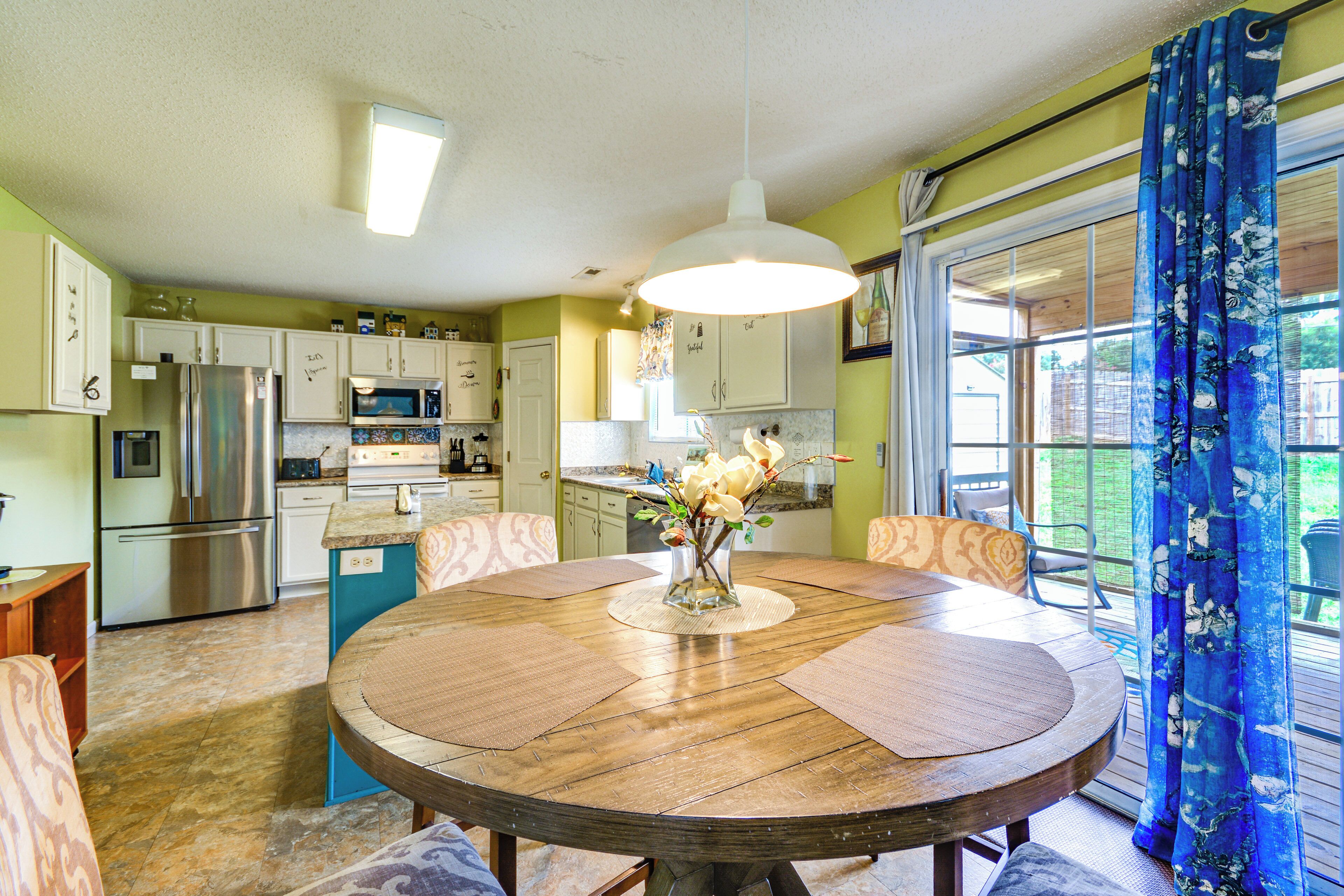 A dining area with a round wooden table, chairs, and a vase with flowers.