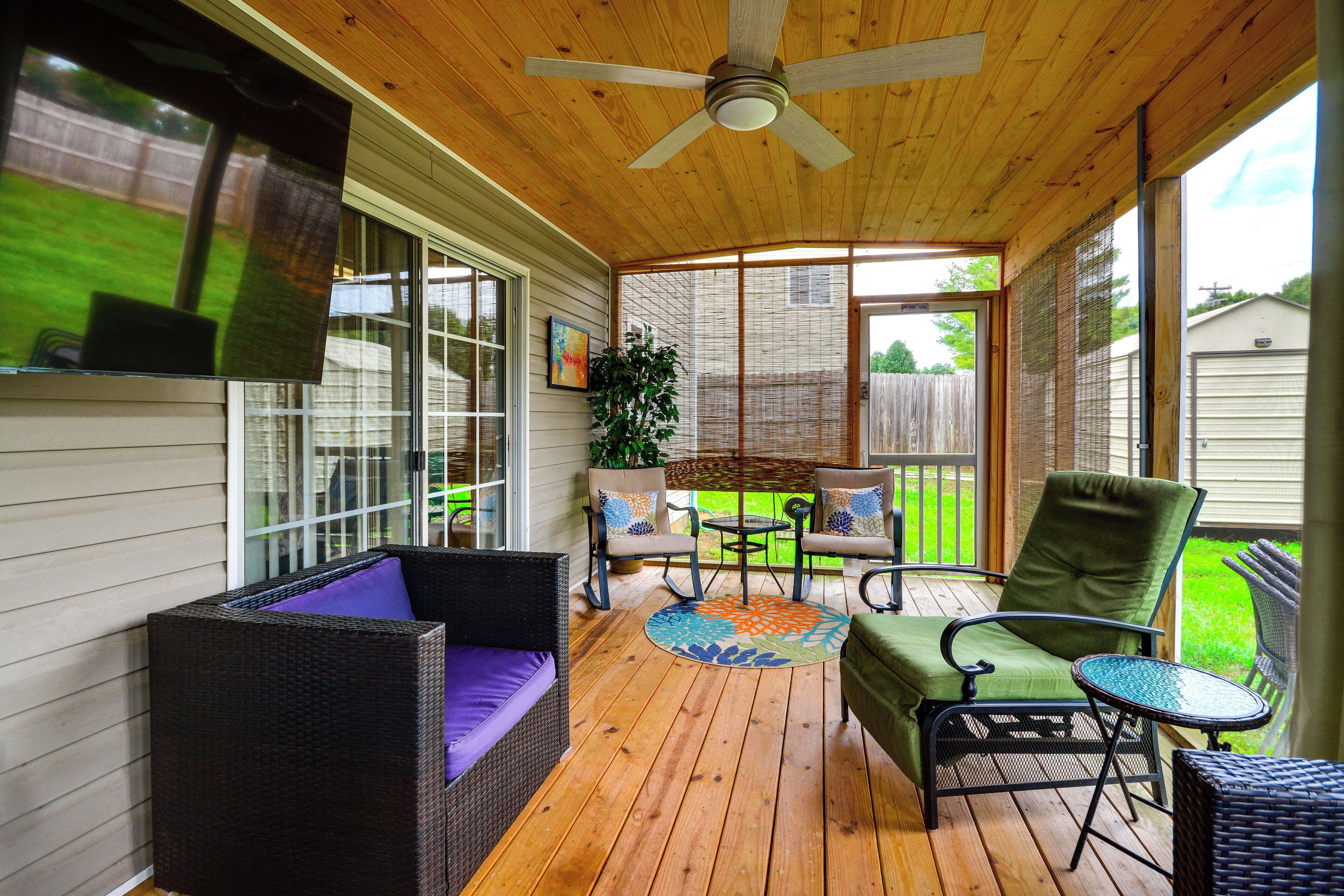 A covered porch with wicker furniture, a ceiling fan, and a view of the backyard.