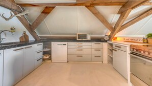 A compact kitchen with a skylight, wooden beams, and modern appliances.