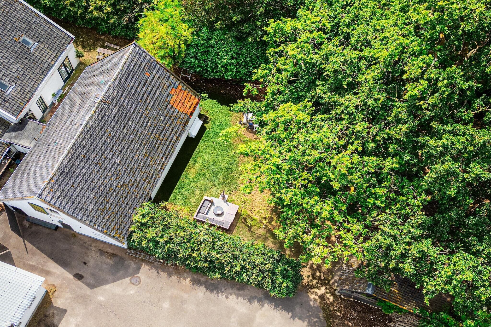 An aerial view of a residential area with a house, a small garden, and a paved driveway.