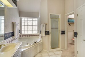 Un baño con bañera, lavamanos, ventana y ducha.