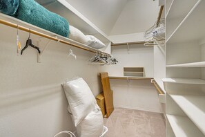 Ein begehbarer Kleiderschrank mit offenen Regalen, einer Kleiderstange und einer Aufbewahrungsbox.
