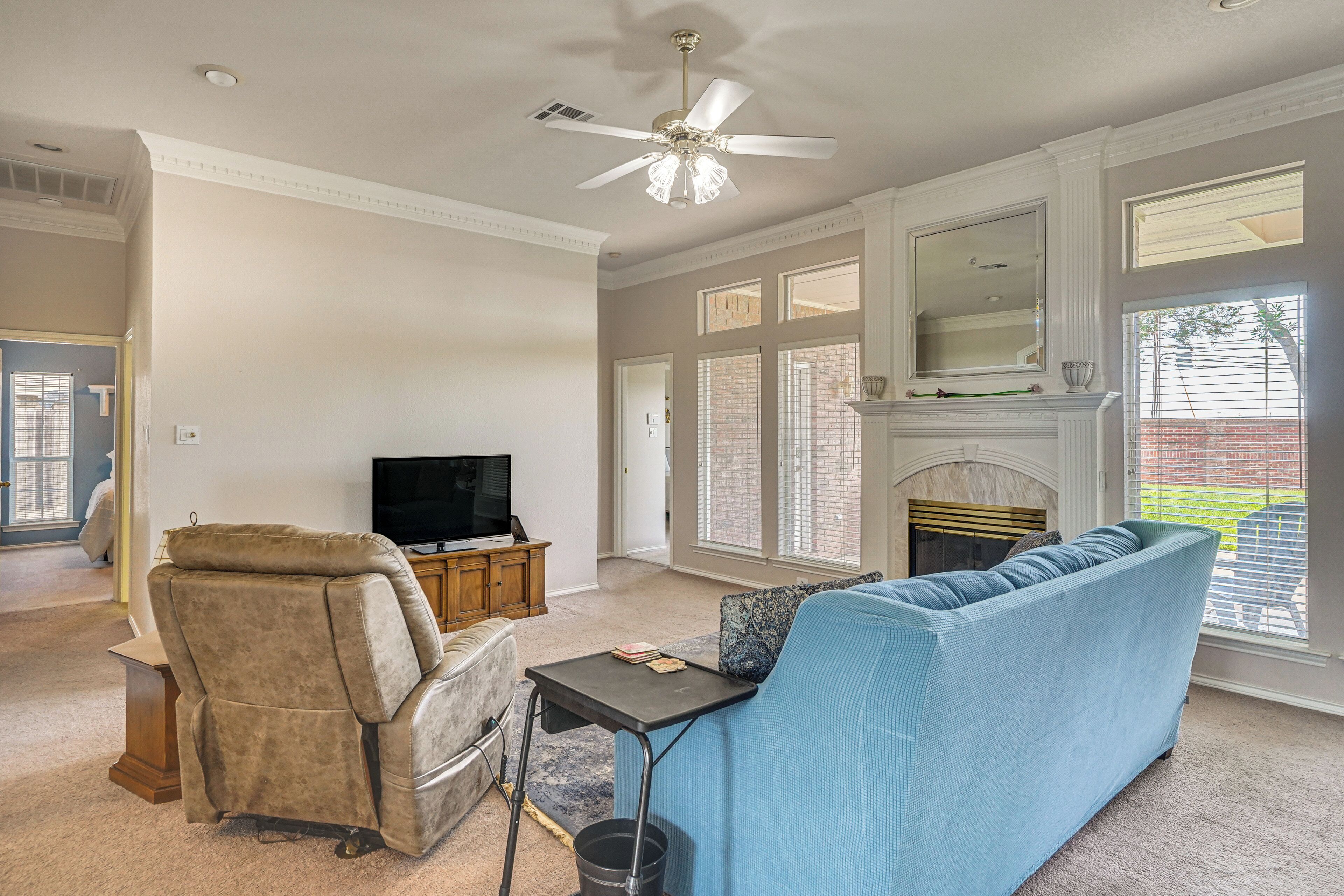 A living room with a sofa, a television, a fireplace, and a ceiling fan.
