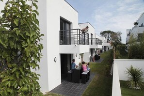 A modern residential building with a flat roof, multiple balconies, and a small outdoor seating area. - Villa in Anglet between ocean, forests (Anglet)