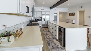 A modern kitchen with white cabinetry, stainless steel appliances, and a central island. - Colorado River Family Escape in Bullhead City (Bullhead City)