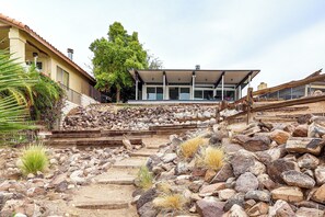 Un bâtiment doté d’un patio, d’un escalier en pierre et d’une végétation luxuriante tout autour.