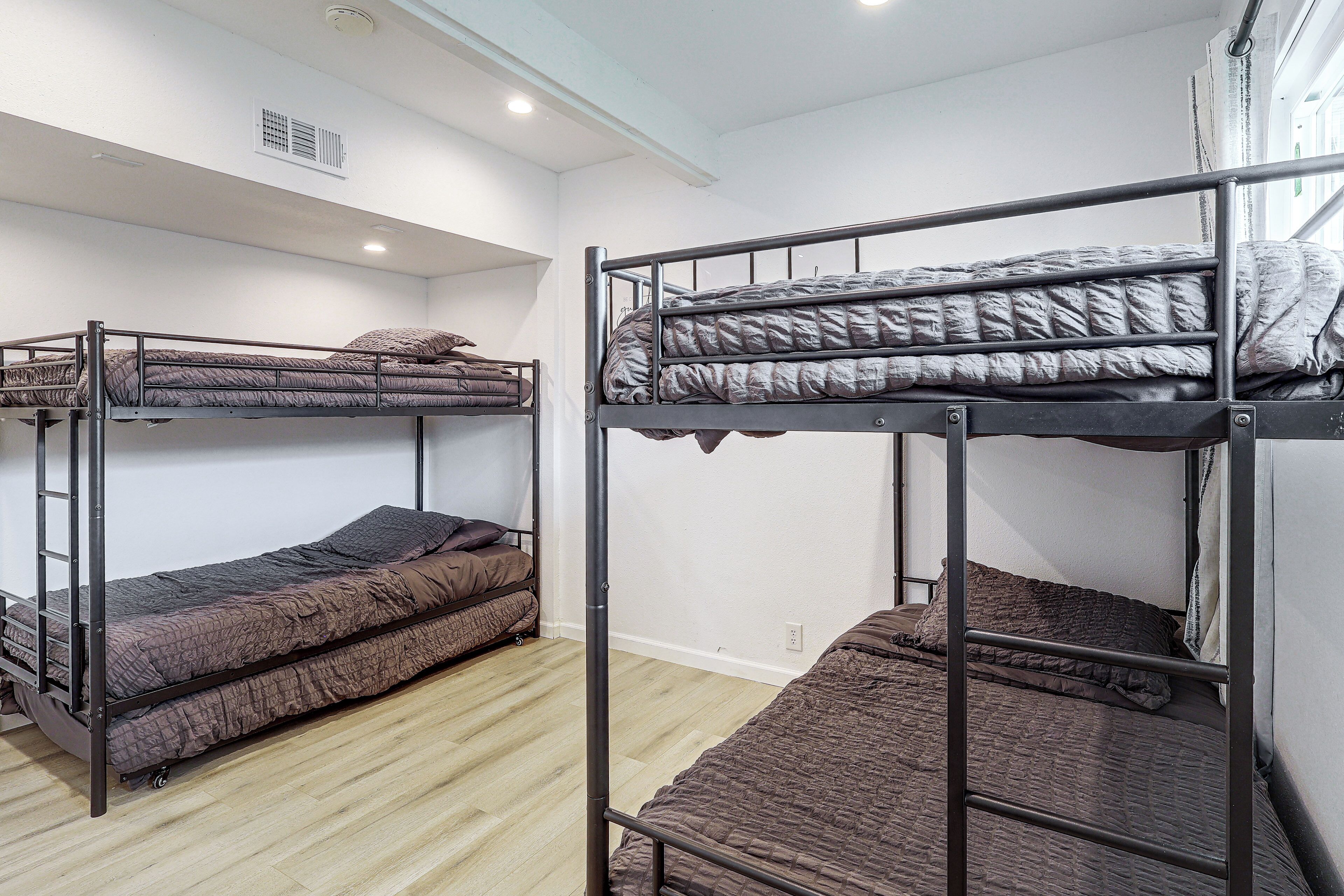 Un dormitorio con literas, suelo de madera y pared blanca.