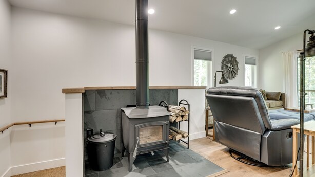 A modern living room with a wood-burning stove, a leather sofa, and a dining area. - Newly Built Wooded Getaway in Grand Junction (Grand Junction)