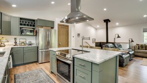 A modern kitchen with a central island, built-in appliances, and a dining area with a sofa and table. - Newly Built Wooded Getaway in Grand Junction (Grand Junction)