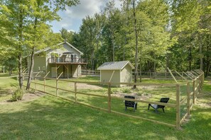 A two-story house with a balcony, surrounded by a fenced yard with a small shed and a chair. - Newly Built Wooded Getaway in Grand Junction (Grand Junction)