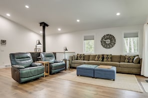 Ein modernes Wohnzimmer mit Ledersesseln, einer Couch, einer Uhr und einem Kamin.