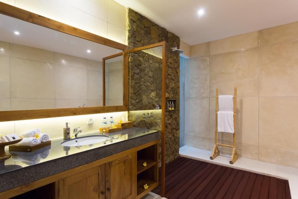 A bathroom with a large mirror, wooden vanity, and a shower area.