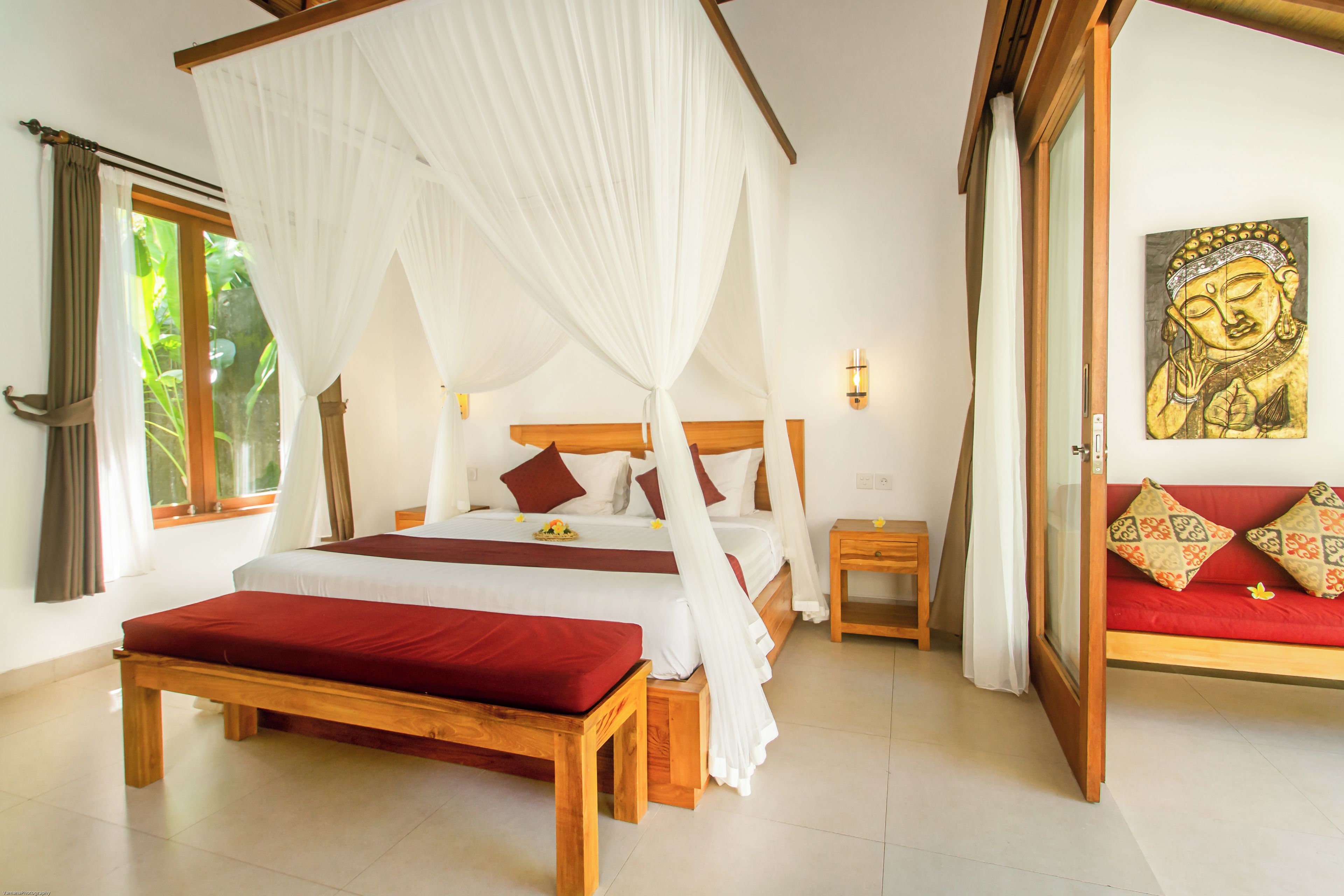 A bedroom with a four-poster bed, a bedside table, a nightstand, and a wall-mounted lamp.