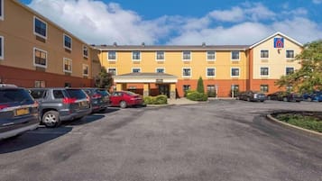 Ein Hotel mit Parkplatz, mehreren Autos und blauem Himmel.