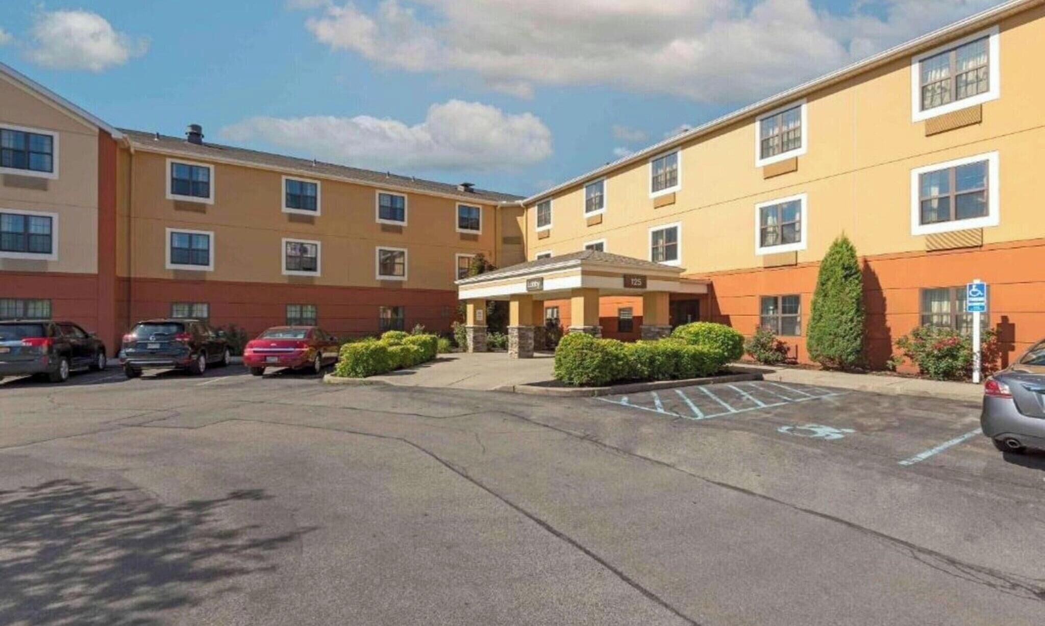 A multi-story hotel with a parking lot, a covered entrance, and a handicap-accessible sign.