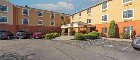 A multi-story hotel with a parking lot, a covered entrance, and a handicap-accessible sign.