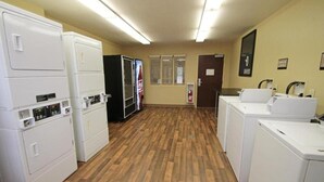 Un cuarto de lavandería con lavadoras y secadoras apiladas, un refrigerador y un área de lavamanos.