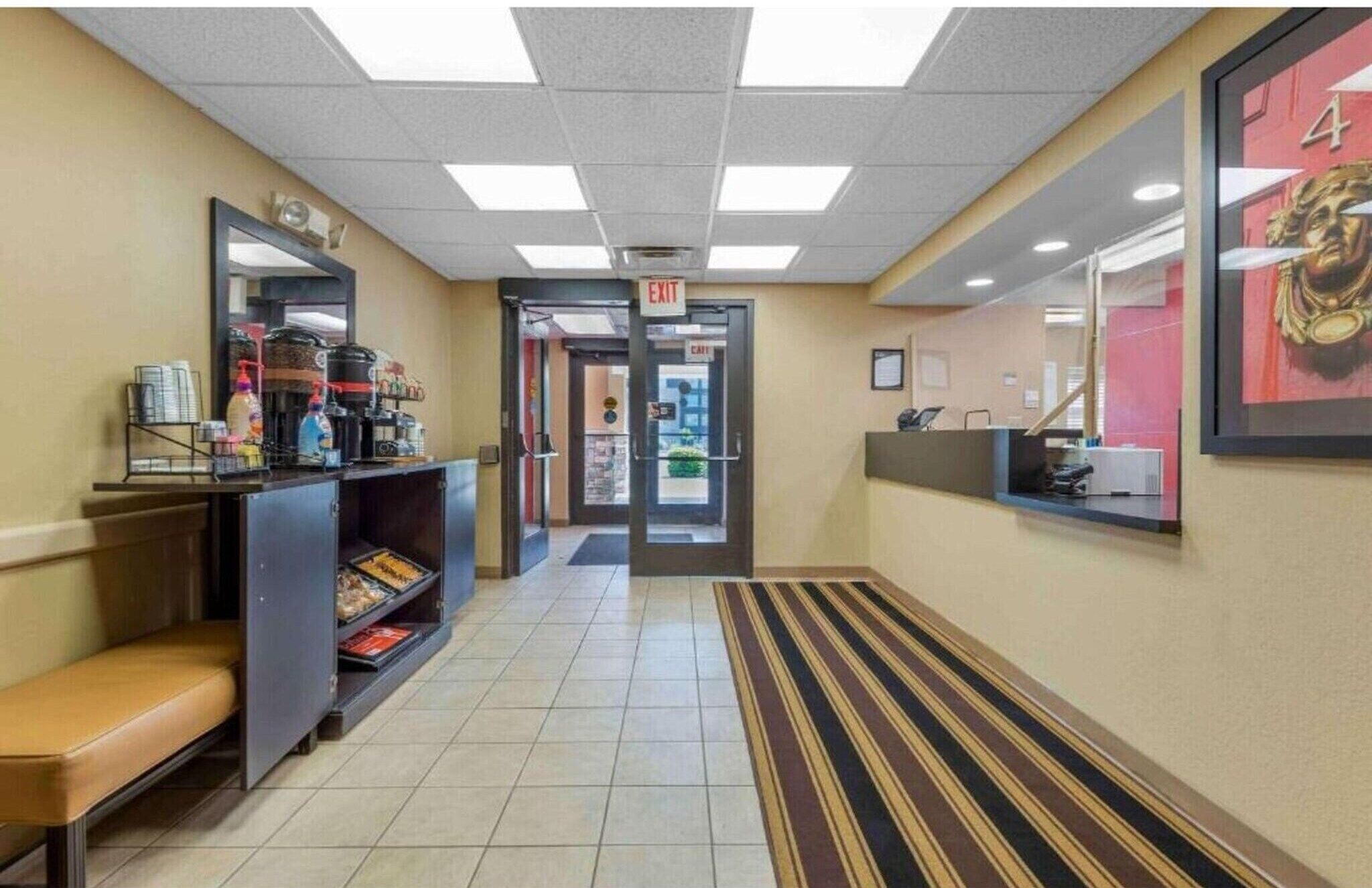 A hotel corridor with a reception desk, a bench, and an exit door.
