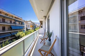 Ein Balkon mit Sitzgelegenheit, einem Blumentopf und Blick auf angrenzende Gebäude.