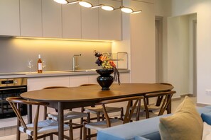 Eine moderne Küche mit Essbereich, mit einem Holztisch, Stühlen und einer Vase mit Blumen.