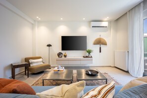 Un salon moderne avec un canapé, une table basse et un téléviseur à écran plat fixé au mur.