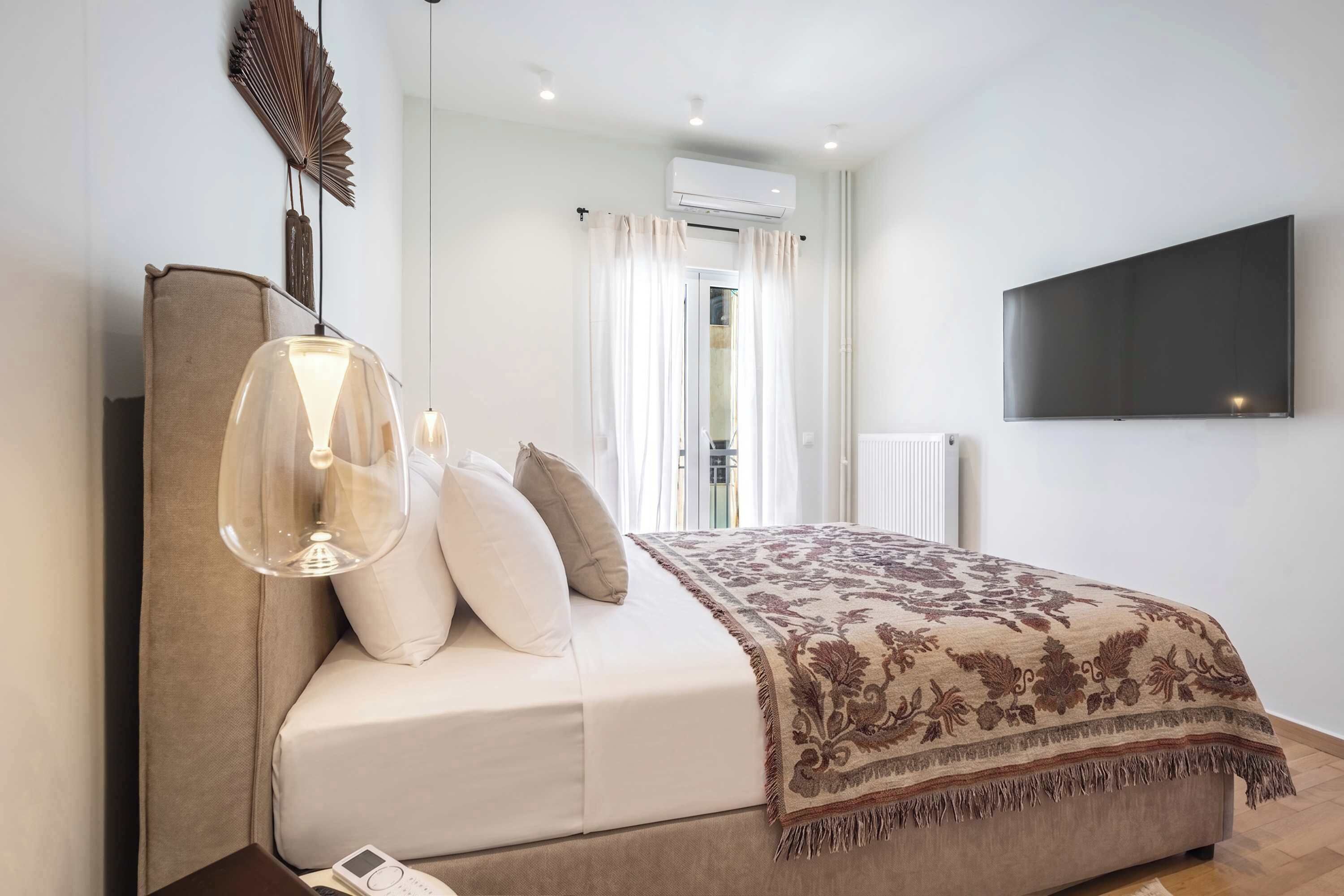 Ein modernes Schlafzimmer mit einem großen Bett, einem an der Wand befestigten Fernseher und einem Deckenventilator.