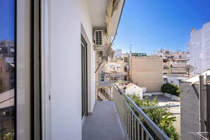 Un balcon étroit d’où l’on peut admirer les bâtiments voisins et un ciel dégagé.
