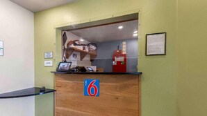 A reception desk with a wooden counter, a blue sign with the number 6, a red fire extinguisher, and a framed notice on the wall. - 2 Full Beds | Non-Smoking, Micfridge (Norman)