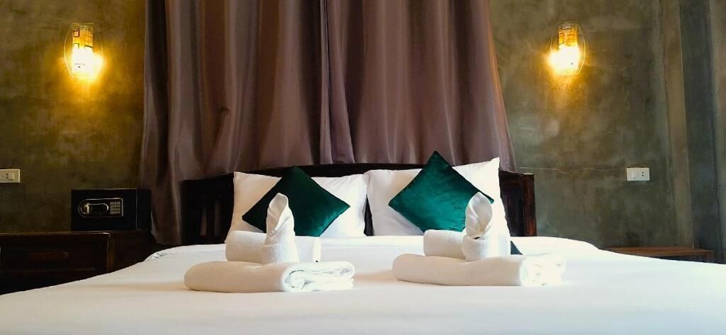 Une chambre d’hôtel avec un lit, des oreillers, une table de chevet et des appliques murales.