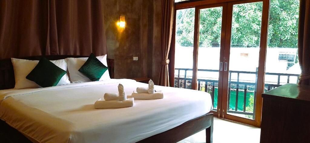 Habitación de hotel con una cama grande, cabecero de madera y vista a través de un ventanal corredero.