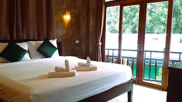 Habitación de hotel con una cama grande, cabecero de madera y vista a través de un ventanal corredero.