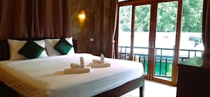 A hotel room with a large bed, a wooden headboard, and a view through a sliding glass door. - Namu Hotel (Pai)