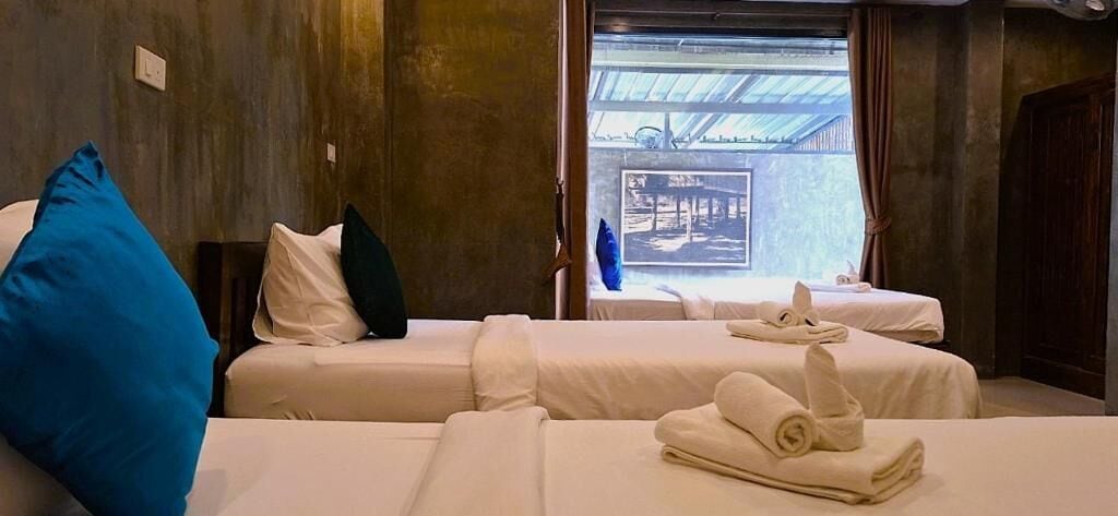 A hotel room with two beds, a blue pillow, and a view of the outside.