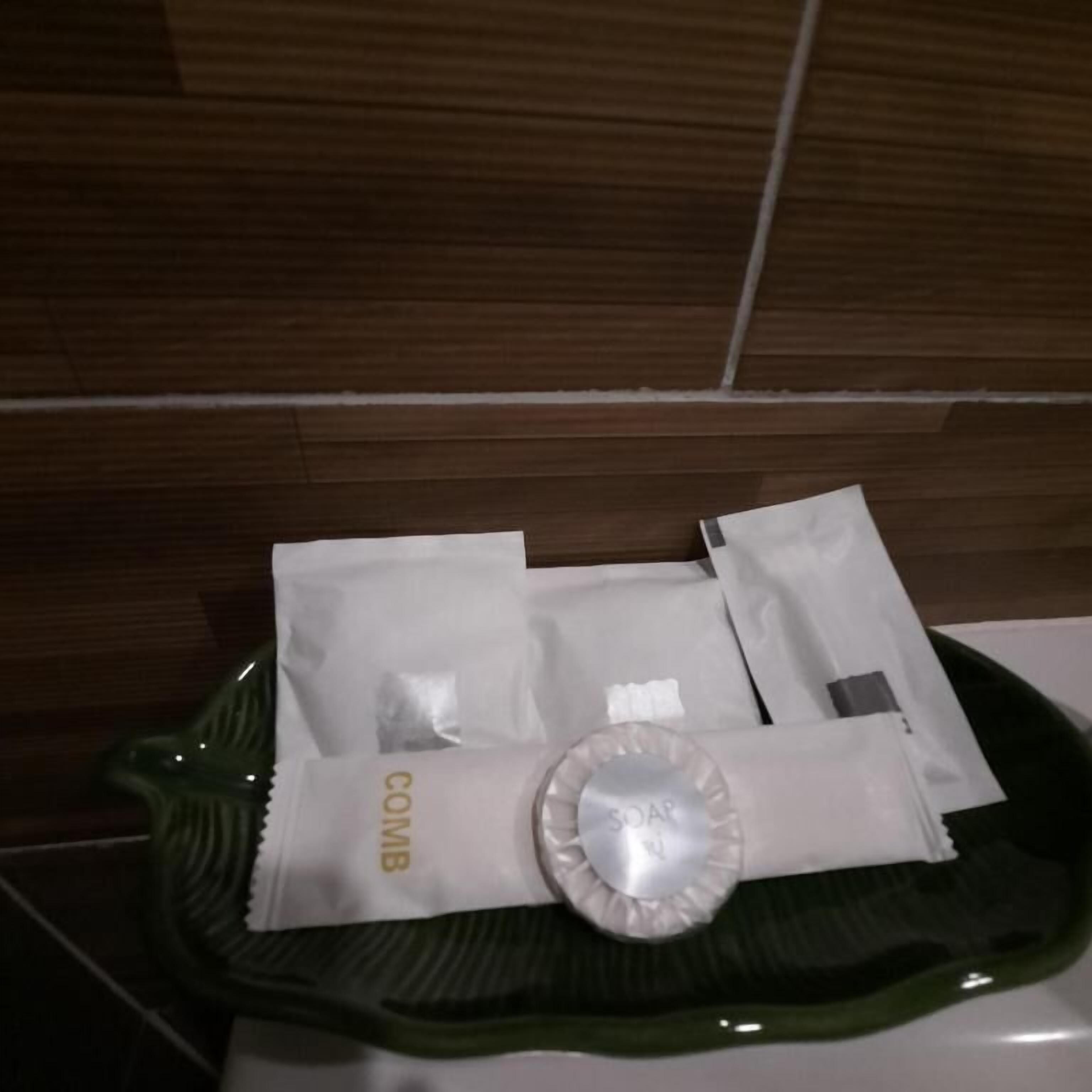 Un plateau vert contenant des articles de toilette, notamment un peigne, du savon et des mouchoirs.