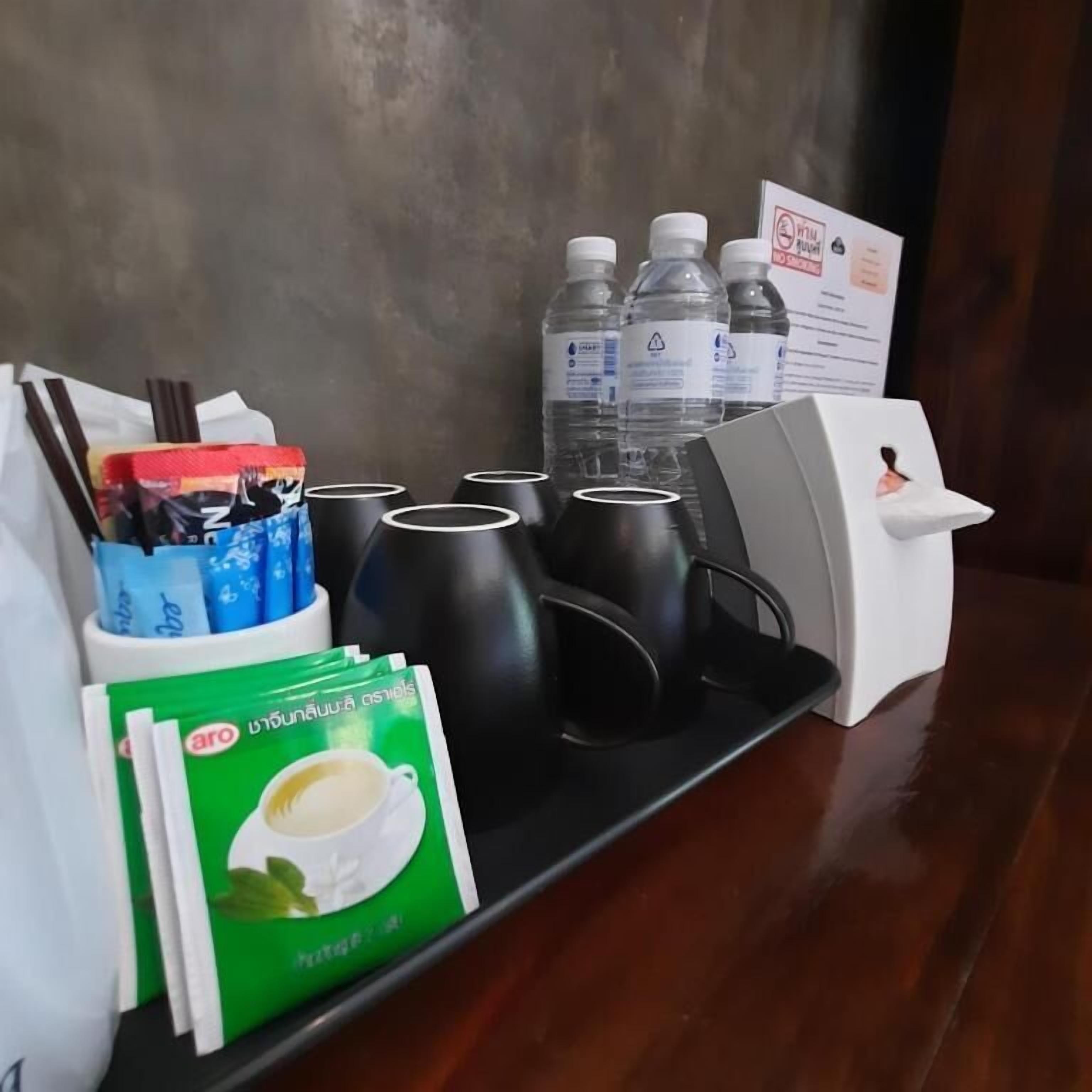 Una bandeja con tazas de café, una caja de pañuelos, una botella de agua y un dispensador de pañuelos.