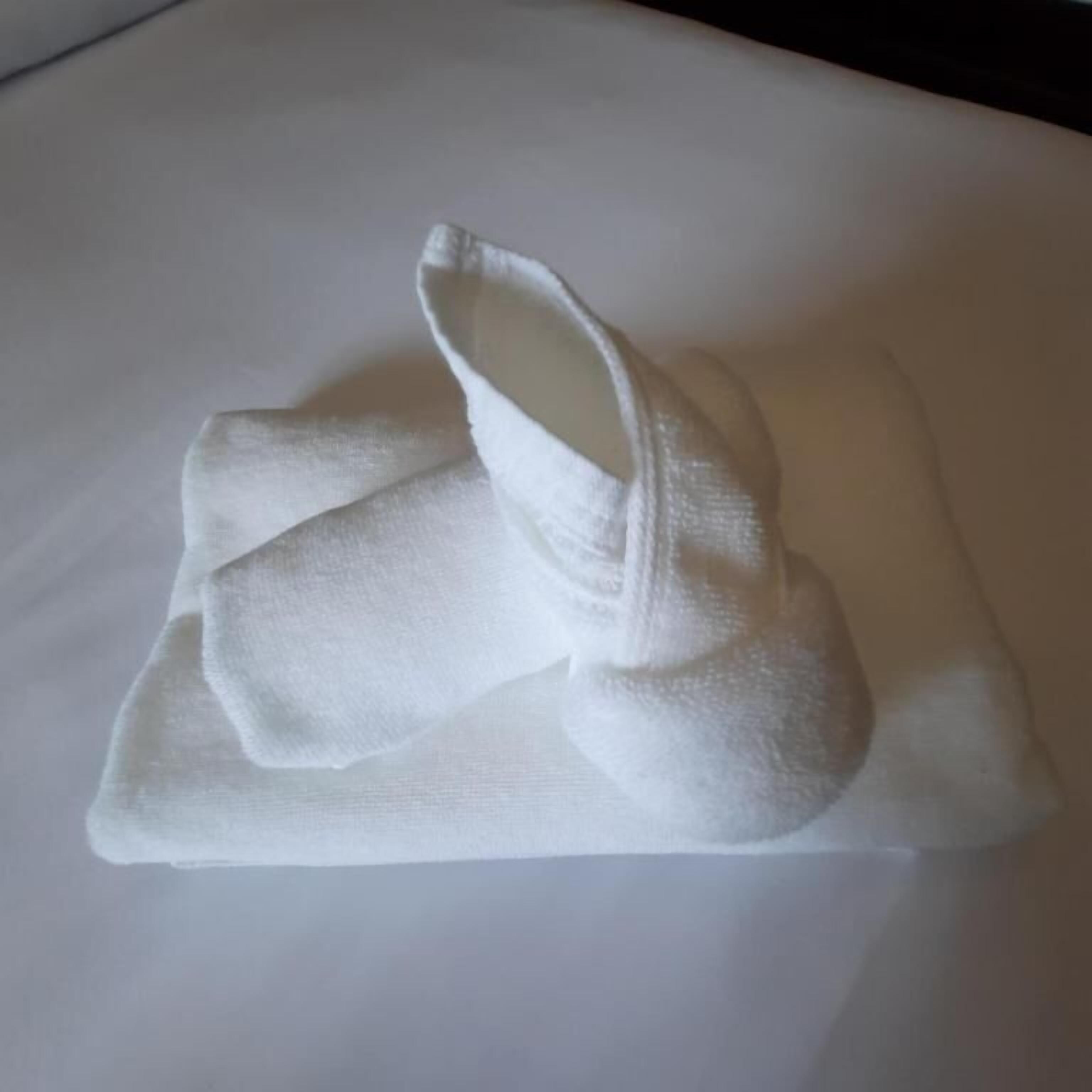 A white towel folded on a white surface.