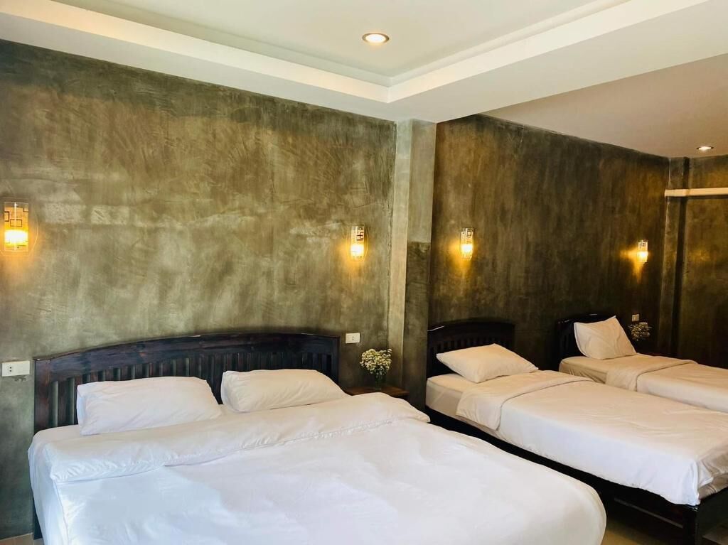 Habitación de hotel con dos camas, cabecera de madera y apliques de pared.