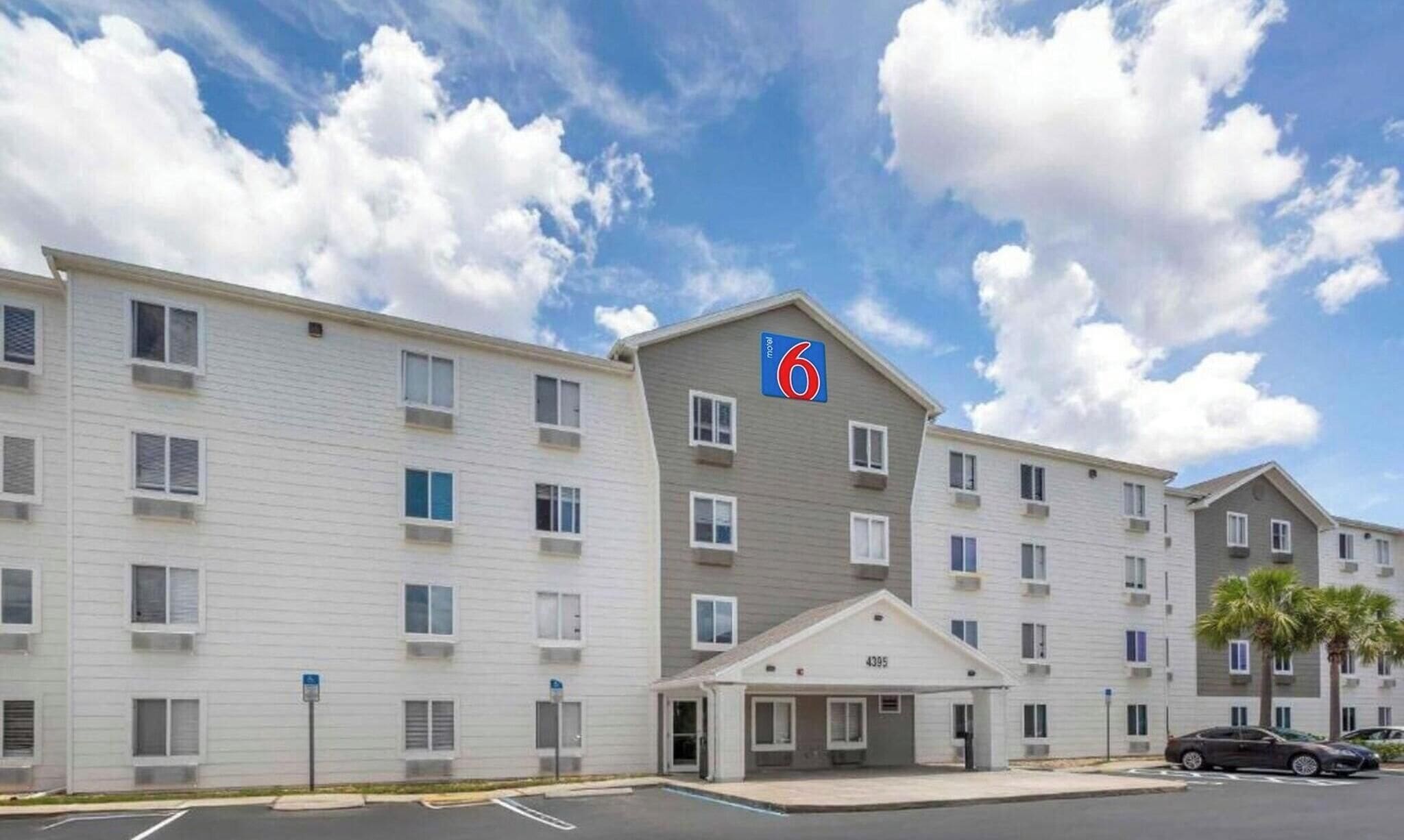 A motel with a flat facade, multiple windows, and a parking lot.