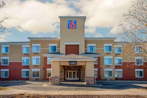 A motel with a prominent '6' sign, a lobby entrance, and a parking lot.