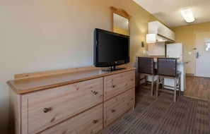 Ett hotellrum med en byrå i trä, en tv, ett skrivbord med två stolar och en spegel.