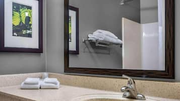 Un baño con lavamanos, espejo y toallero.