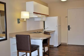 Una kitchenette pequeña con una encimera, un lavabo, un refrigerador y una silla.