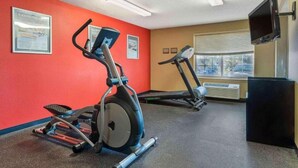 Un gimnasio con cintas de correr, elíptica y un banco de pesas.
